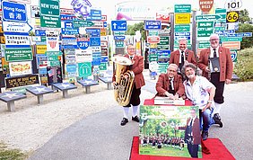 hier sind Schilder vom Fernweh-Park in Hof zu sehen und 4 Männer vom Blasorchester